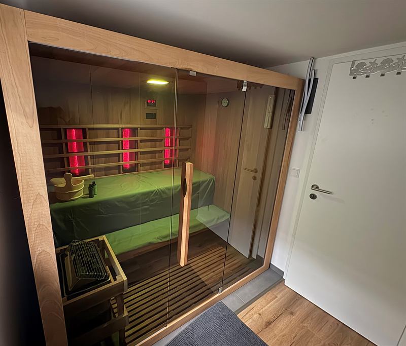 Hybridsauna im Untergeschoss mit eingeschaltetem Infrarotstrahler und warmem Lichtspiel